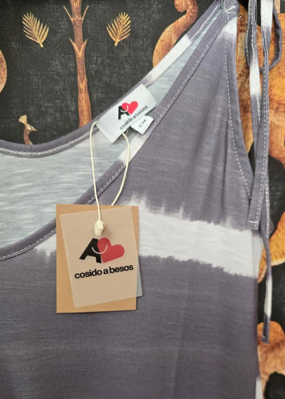 Destalles de un vestido de tirantes gris con estampado a rayas y bajo en volante